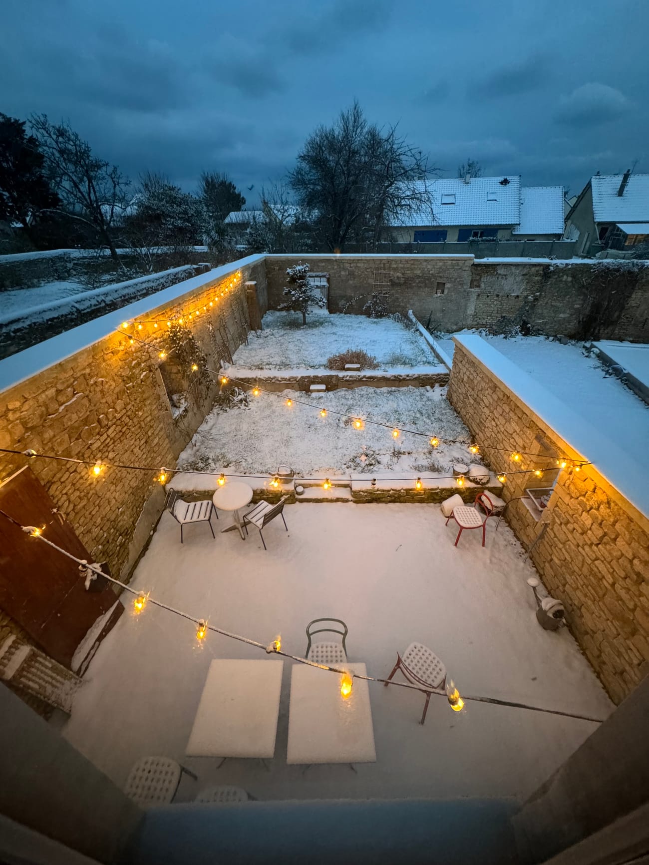 Le jardin clos des Briques sous la neige, un soir, guirlandes allumées