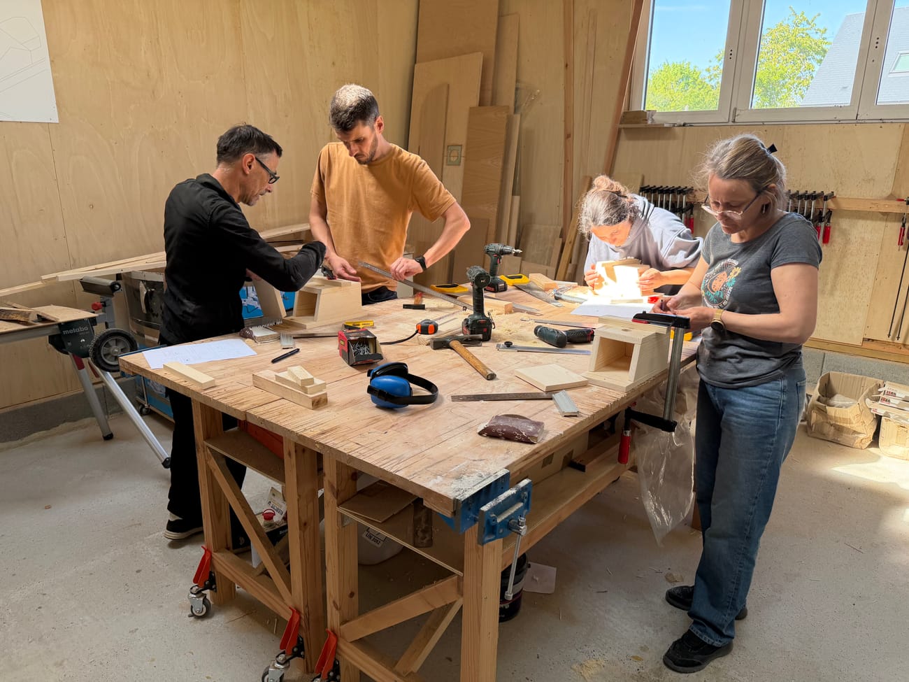 Four participants at the workbench during a wood team building