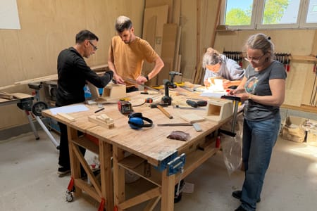 Four participants at the workbench during a wood team building
